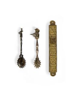 Cast hollow brass case, long slender rectangle in form, with window at upper portion protected by hanging brass plate;  oval tabs at either end pierced to allow nail for hanging. Overall cast Hebrew inscription.  L:  7 3/4 inches