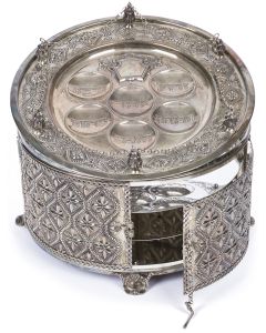 Of circular form case, with pair of large hinged doors set with lock-bar, three interior tiers; detachable upper seder-tray with six labelled oval depressions for ritual foods. Height: 8.5 inches; Diameter: 13 inches.