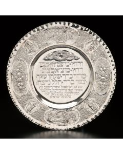 Handwrought and chased with the Hebrew Order of the Seder at center and Psalms 128:2-6 below, floral and fruit designs along wide rim, interspersed with historiated vignettes. Diam: 16 inches.
