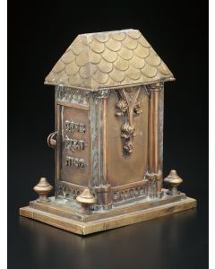 Of house-form in the Gothic style. Coin-slot set at top of shingled roof, side hinged door applied with Hebrew letters “Charity Saves from Death” (Proverbs 10:2). 9.5 x 8 x 5 inches.