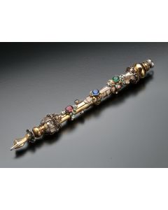 Elaborately decorated in an organic style with curled vines and leaves coupled with colored glass gemstones and painted enamel highlights terminating with a vine-cuffed hand. Length: 11 inches.
