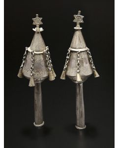 Of conical-form, engraved in registers with geometric design. With Star-of-David finials including the Hebrew word: “Zion.” Five pendant bells on chains and tubular staves. Height: 8 inches.