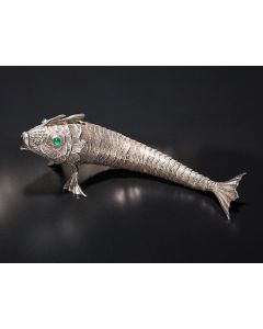 Scaled body with many articulated joints and amphibious-like fins; hinged head, with eyes inlaid with green cabochon stones surrounded by flower-like sockets. Length: 9 inches.