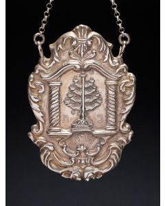 Cartouche shape, wrought and chased with scroll border, centered by nine-branch Menorah surrounded by columns and swan-neck pediment. Hebrew engraving: “Sabbath” below. Suspension chain. Marked. 5.5 x 3.75 inches.