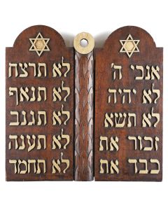 In the form of the Decalogue, with gold-painted Hebrew initial words of each of the Ten Commandments. Central decorative foliate band figuratively joins the two arched tablets. With hanging element on rear. 23 x 23 inches.