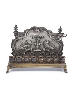 Rococo backplate embossed with two lions flanking a menorah on textured ground. Eight oil containers at front, with a small associated auxiliary light. H: 22 cm (8 inches).