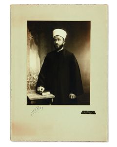 (Grand Mufti of Jerusalem, 1897-1974). Three-quarter length, silver-print photograph by C. Raad of Jerusalem, with Husseini autograph signature below.