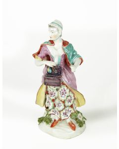 Richly attired and clasping a box of trinkets. Set on a flower-strewn base. Height: 7 3/4 inches (19.7 cm).