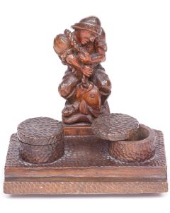 Carved pentagonal base with depressed pen channel, two hinged-lidded inkwells, featuring prominent fisherman statuette. Carved on base: “Made in DP Camp Germany 1949.”