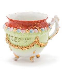 Urn-shaped, footed tea cup hand painted with gilt, floral and garland motif encircling, bearing Hebrew inscription: “Chag Pesach.”