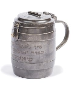 Tankard-shaped, with hinged lid and raised coin slot atop. Simple, striated design bearing Hebrew inscription: “Belonging to The Benevolent Society for Orphans and the Poor, Schoettland.” Height: 5 inches; Diameter excluding handle: 3.5 inches.