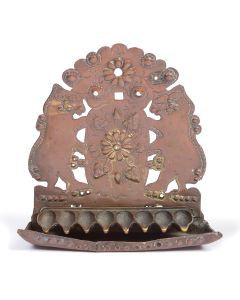 Scalloped sheet-brass backplate pierced with rampant animal figures flanking shield embossed and tooled with floral and grape motifs, punch-beaded border. Traces of gilding. Cast row of oil fonts attached over drip-pan. 10 x 9.75 inches.