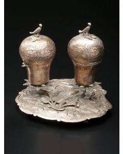 Two pear shaped engraved containers with bird finials above hinged lids, set on an oval form plate chased on matted ground with floral and leaf design centered by two doves flanking a heart; on four paw supports. Marked. 5.5 x 7 inches.