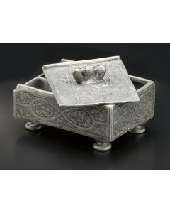 Rectangular box with interior compartments, sliding cover with bird finial, etched with decorative scroll and leaf designs. Set on four rounded supports. Inscribed below with Hebrew letters “Peh-Lamed.” 3 x 2.5 inches.